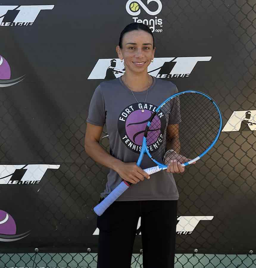 Hitting partner Karen Jiménez holding her racquet in front of the RTT League banner