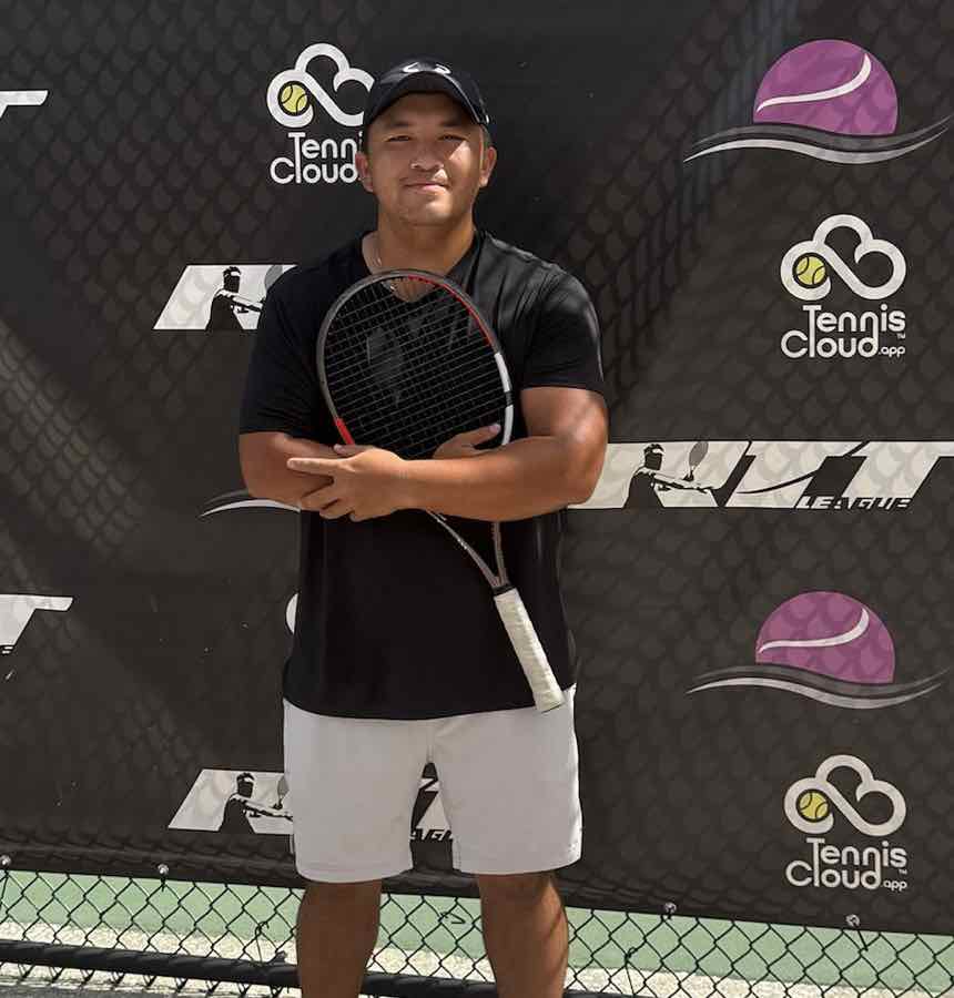 Coach Peter Tong holding his racquet in front of the RTT League banner